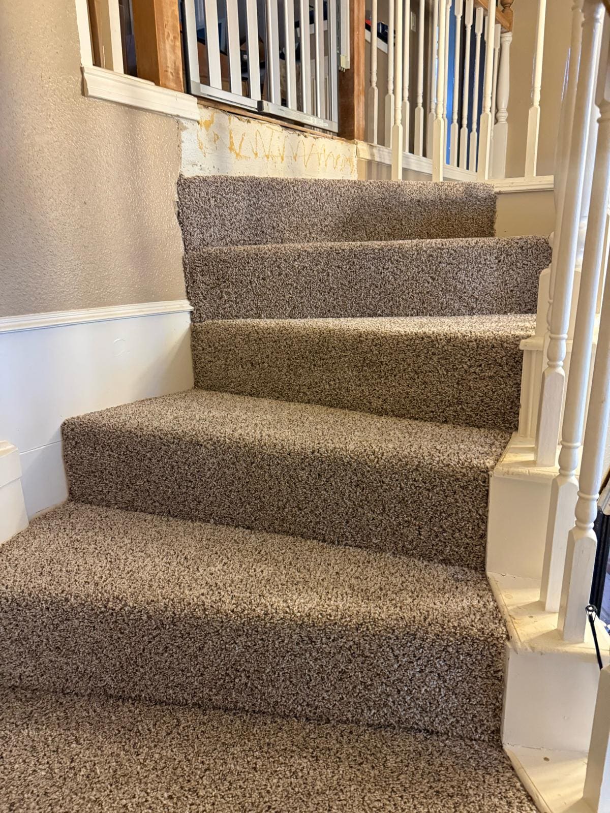 Textured carpet fitted to a staircase and landing, running up beside a white-painted balustrade.